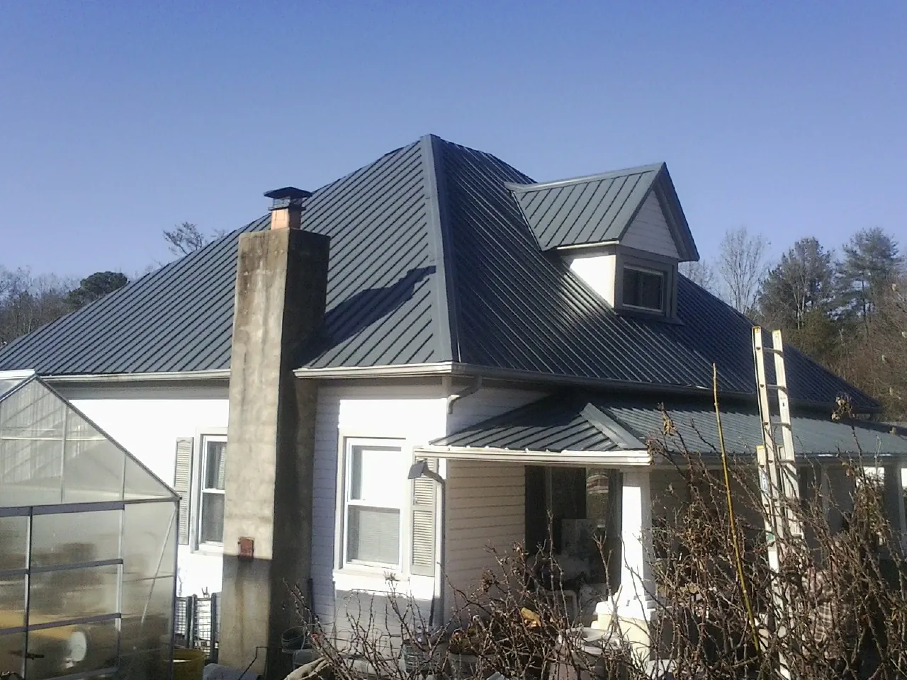 Dark blue standing seam metal roof on a white farmhouse with dormer — Slate & Tile Roof Repair by Roofing Brothers in Ransom