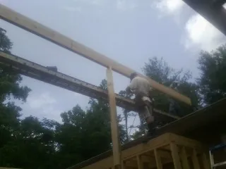 Carpenter setting a ridge beam over a new addition frame — Ice Dam Removal by Roofing Brothers in Ransom