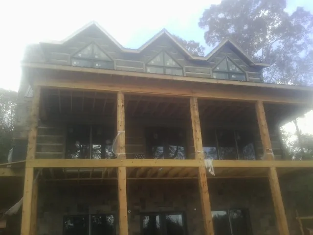 Dormers and porch framing on a large log home under construction — Roof Coating work by our crew in Ransom