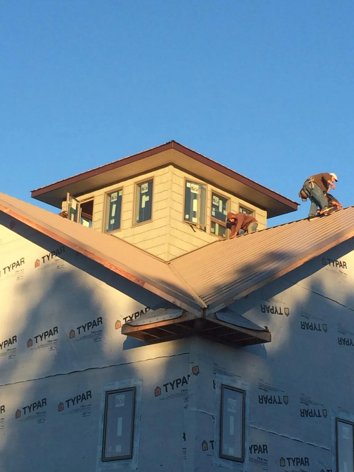 Roofers working around a rooftop cupola on a new metal roof at sunset — Roof Waterproofing in Ransom by Roofing Brothers